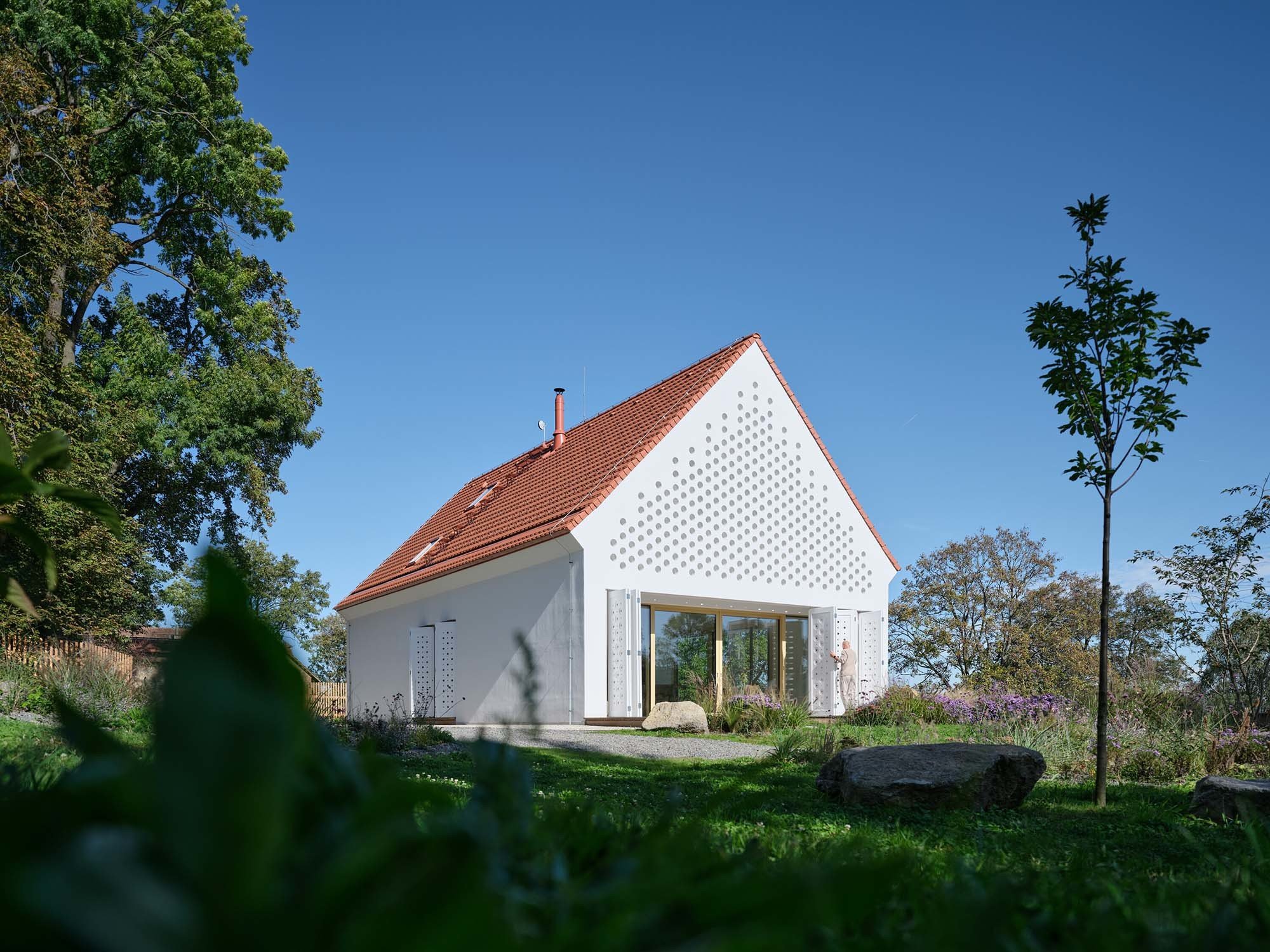 Das House Oskar fügt sich mit seiner perforierten Fassade dezent in einen tschechischen Schlosspark ein. Das Muster wiederholt sich an den Holzpaneelen vor Nischen und Loggien.