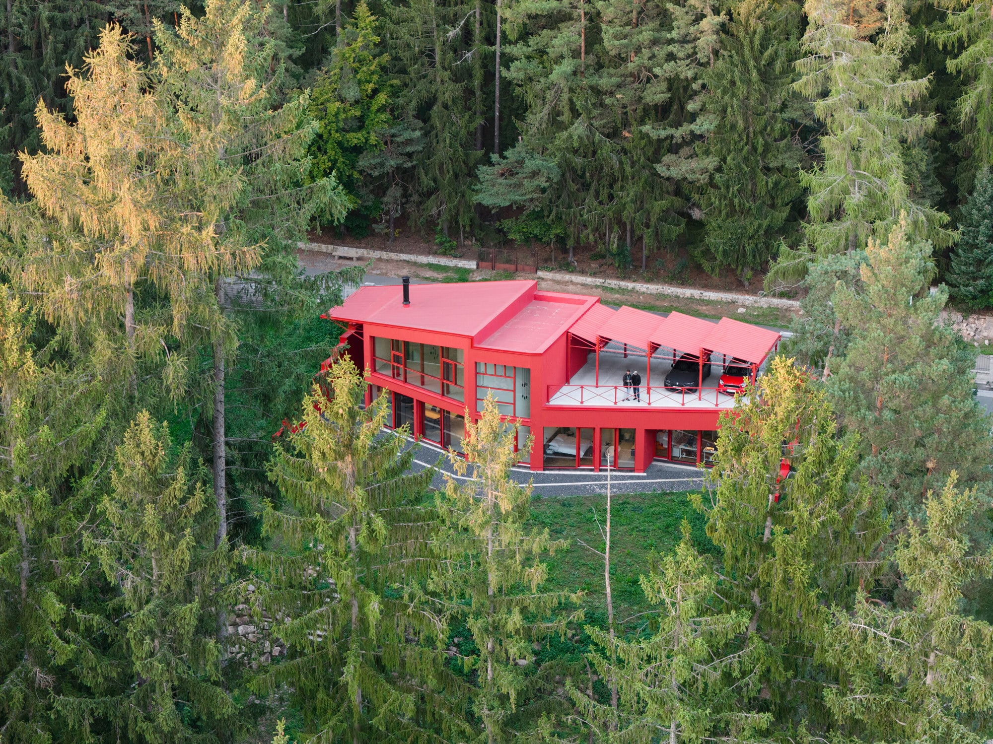 Das Haus ist als länglicher Bau an der Dorfstraße platziert. Zu dieser Seite zeigt es sich als niedriger, geschlossener Baukörper. Gleichzeitig öffnet es sich zum nach Süden ausgerichteten Hang mit dichtem Baumbestand.