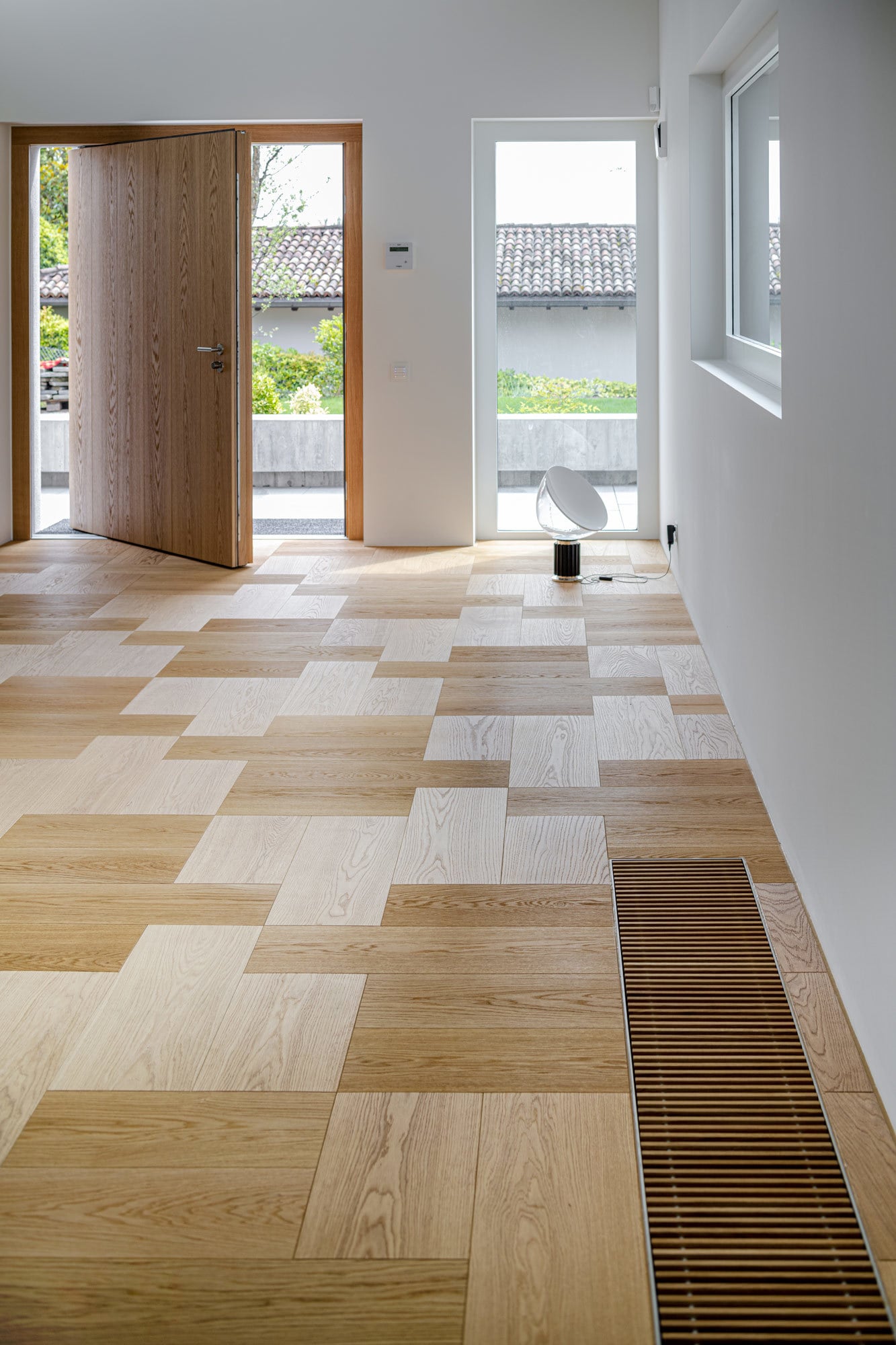 Details wie die Lüftungsgitter aus Eiche, um die das Parkett herumgelegt wurde, lassen die Räume wie aus einem Guss wirken.