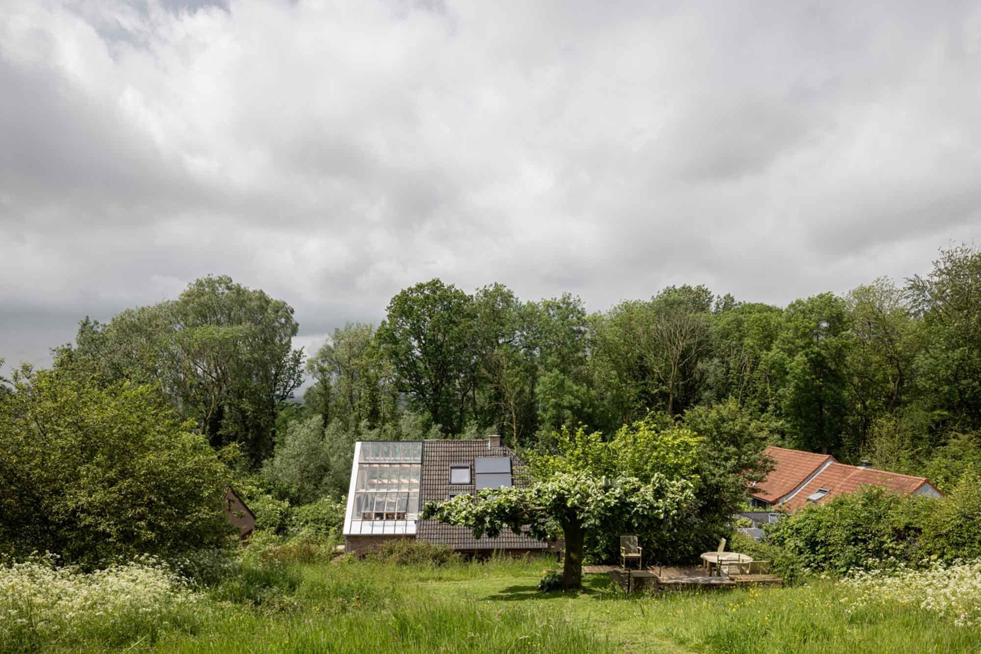 Die flämische Fermette liegt eingebettet in die hügelige Landschaft des Pajottenlands. Der neue Wintergarten schafft eine direkte Verbindung zur Natur.