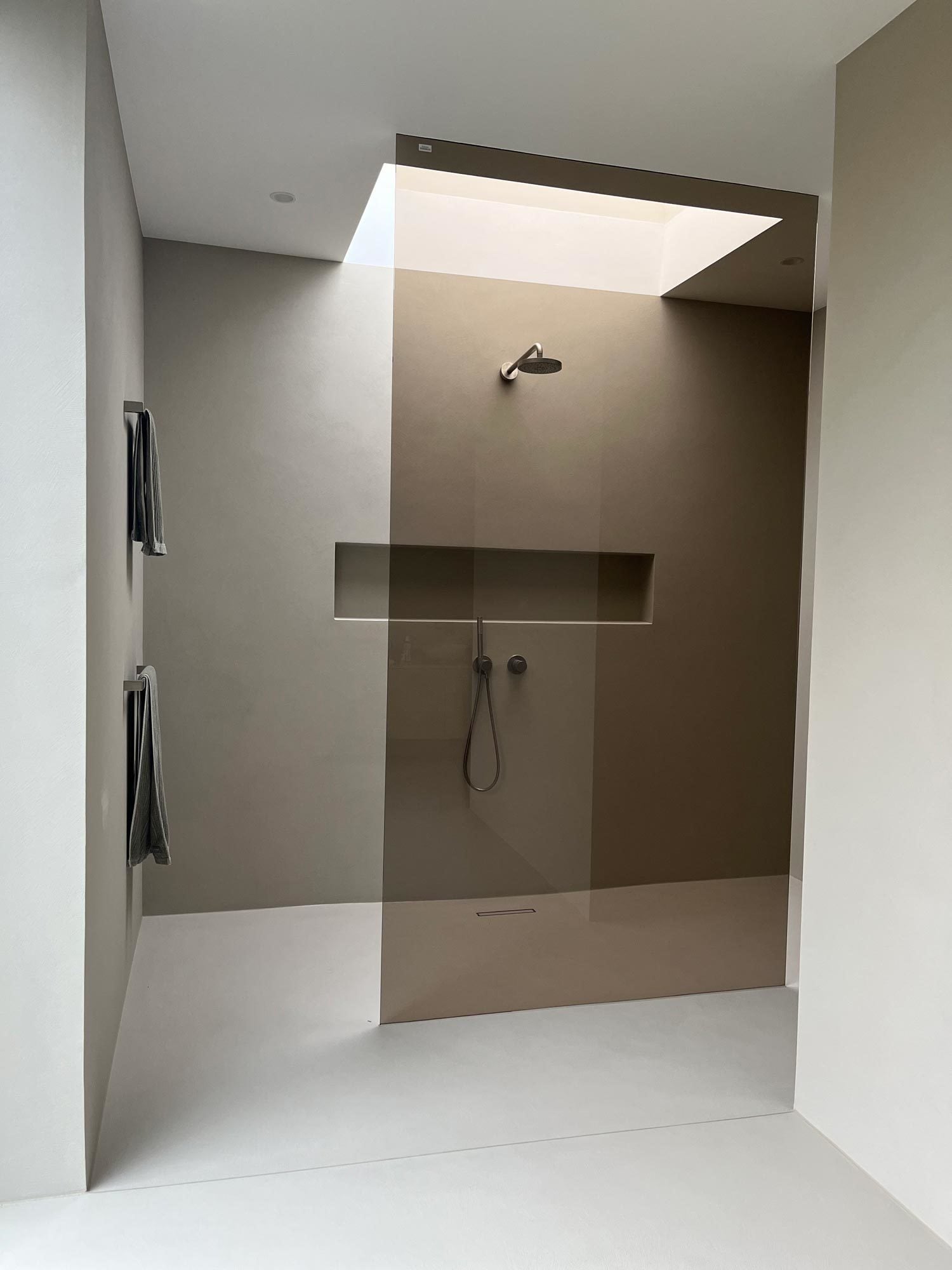 Bronziertes Glas, wandbündige Armaturen, keine sichtbaren Fugen – die Dusche fügt sich nahtlos in die Raumsprache des Hauses ein.