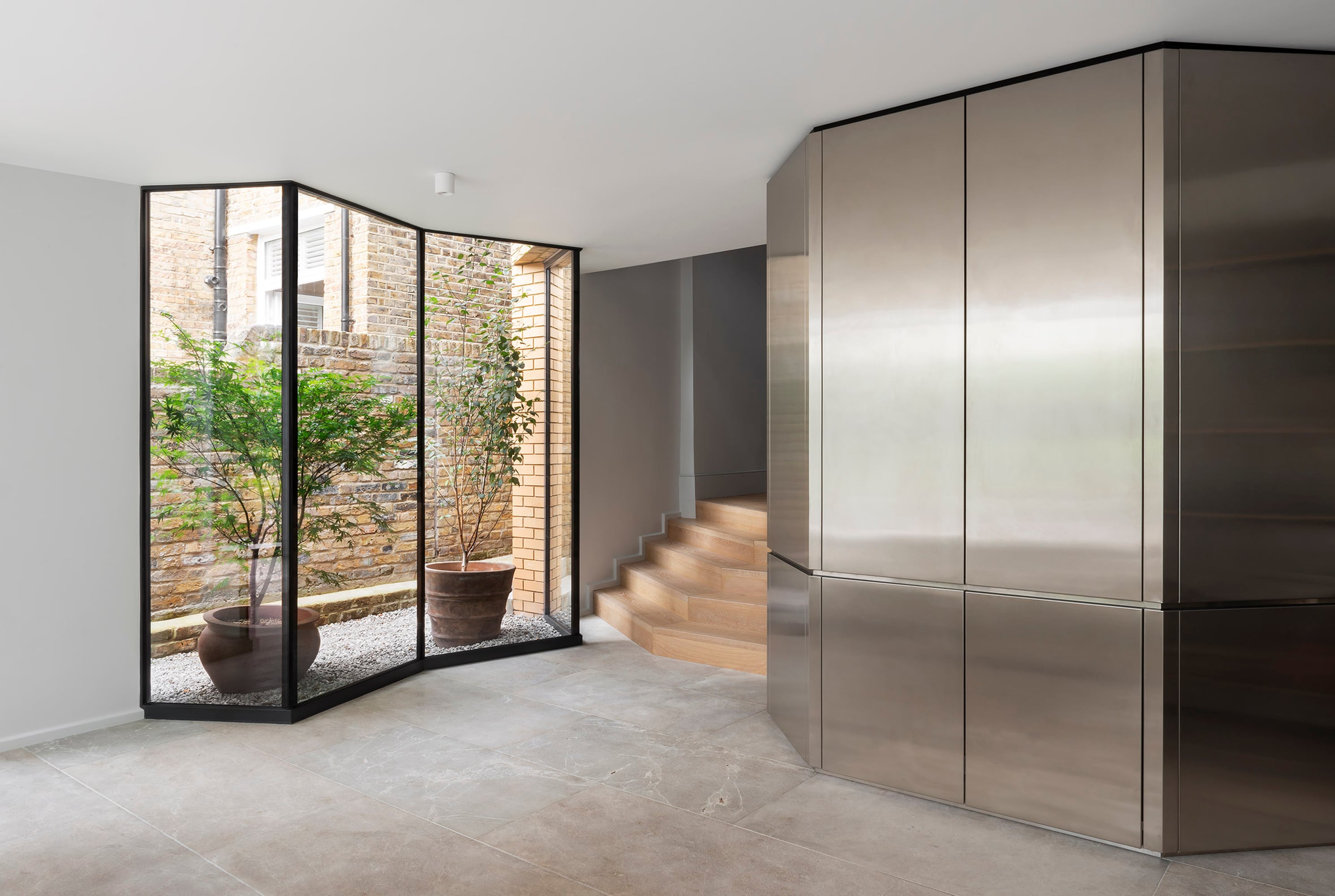 Großzügige Glasflächen verbinden den Wohnraum fließend mit dem Garten und setzen die gefaltete Formensprache fort.