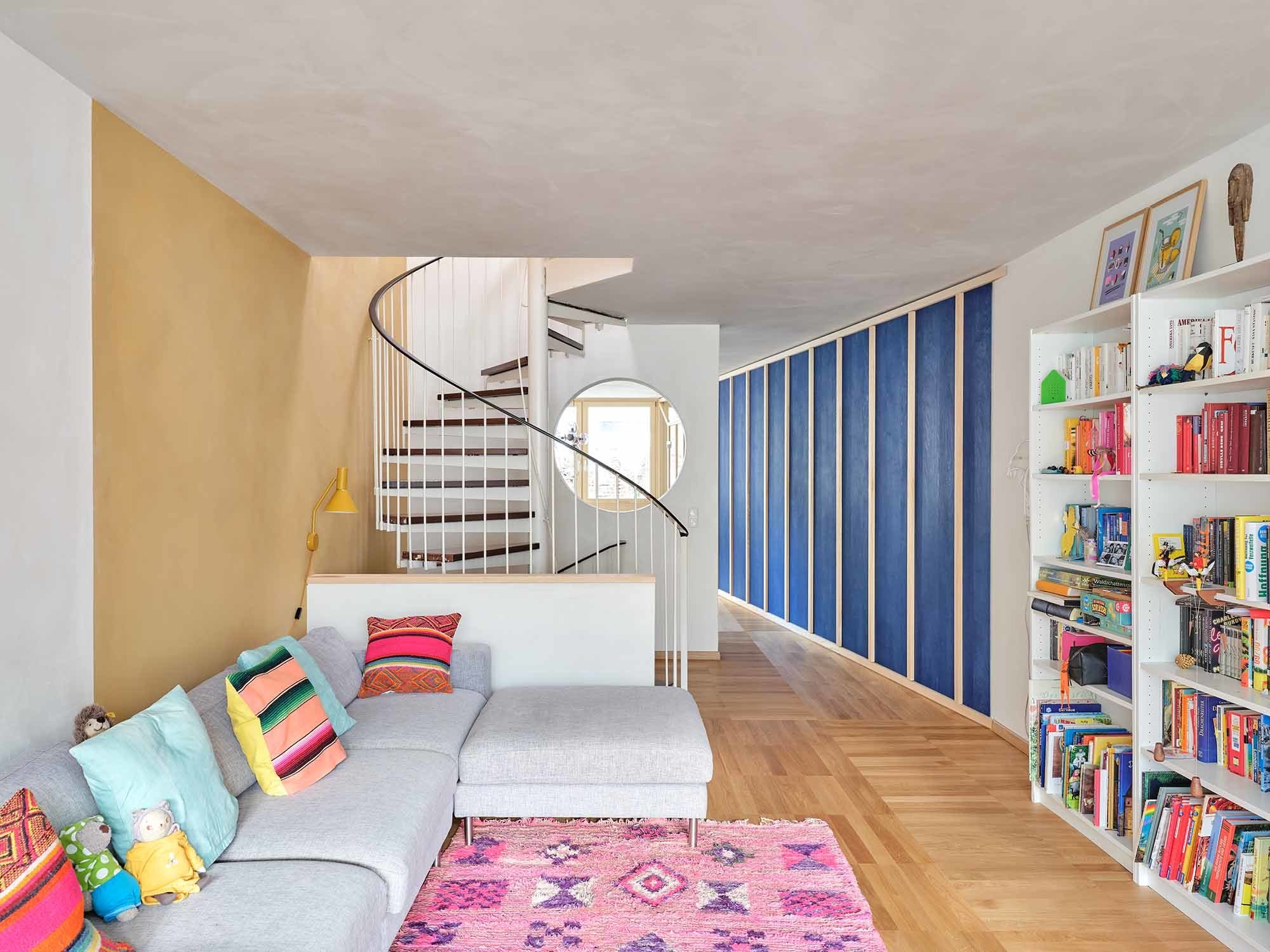 Das warme Ocker des Lehmputzes bringt Sonnenlicht tief ins Haus und verbindet Treppe und Wohnzimmer.