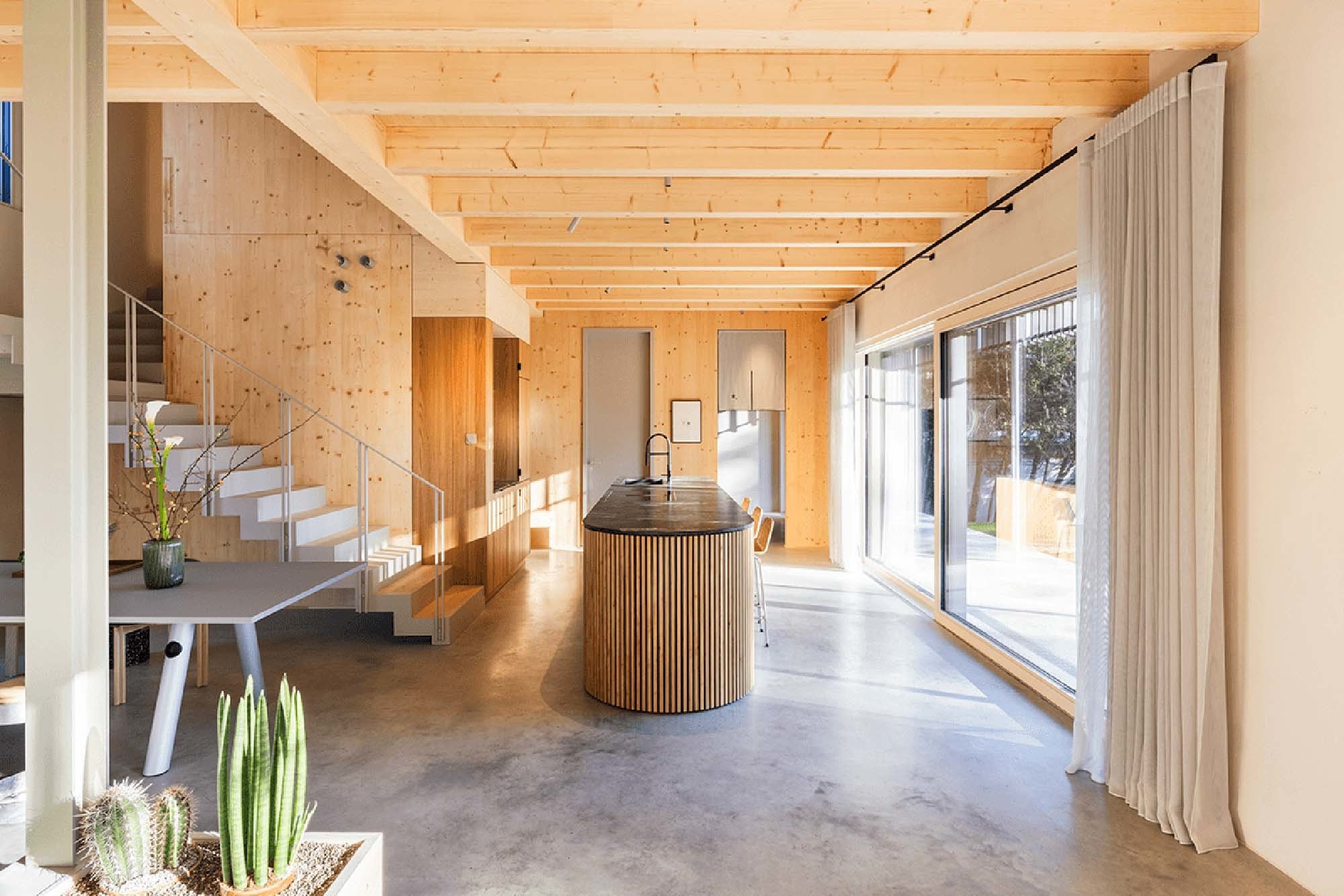 Der offene Wohnbereich mit Küche öffnet sich über große Fenster zum Garten.