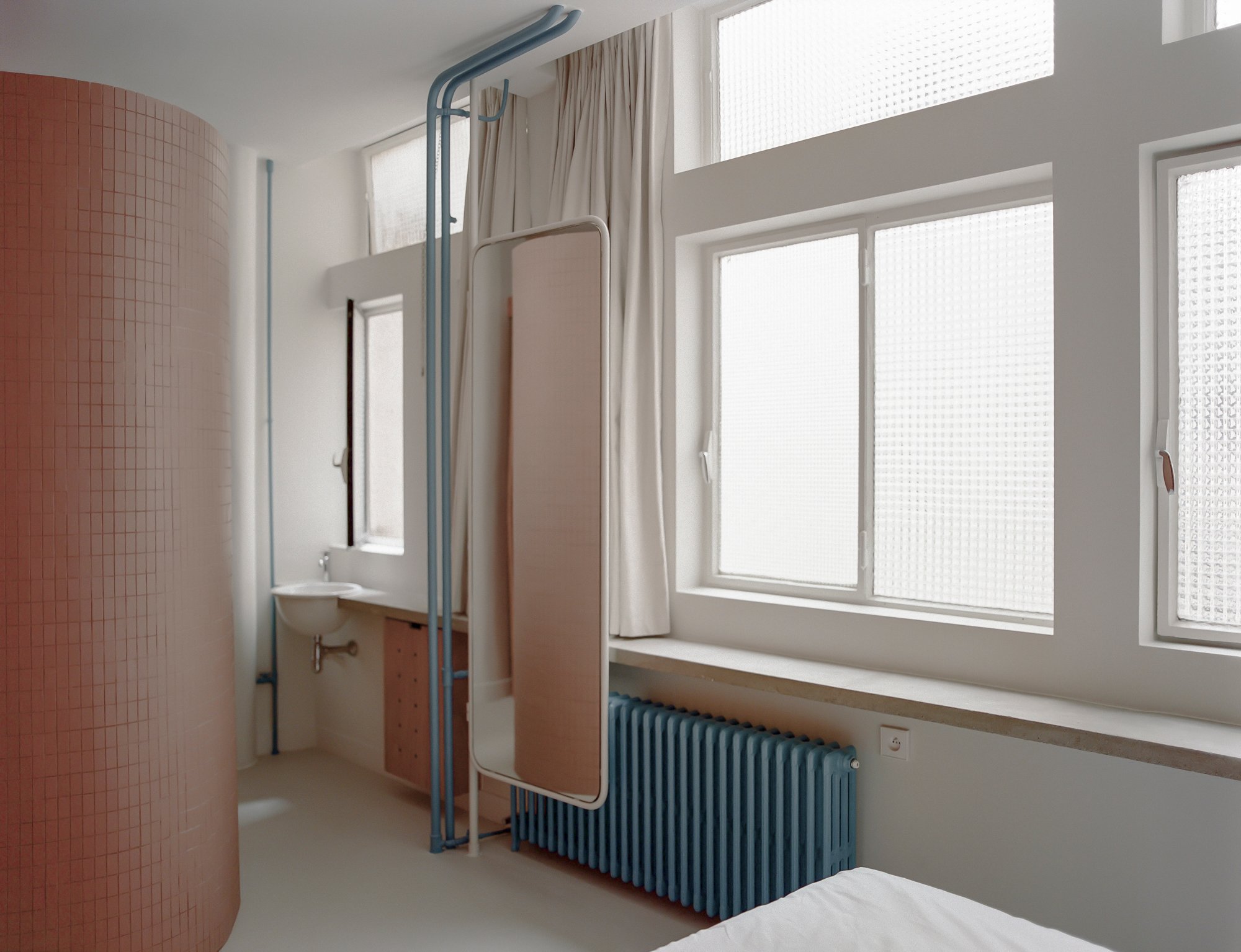 Terrakotta trifft Minimalismus – Die kreisrunde Dusche aus hellen Fliesen setzt ein architektonisches Statement im Schlafzimmer