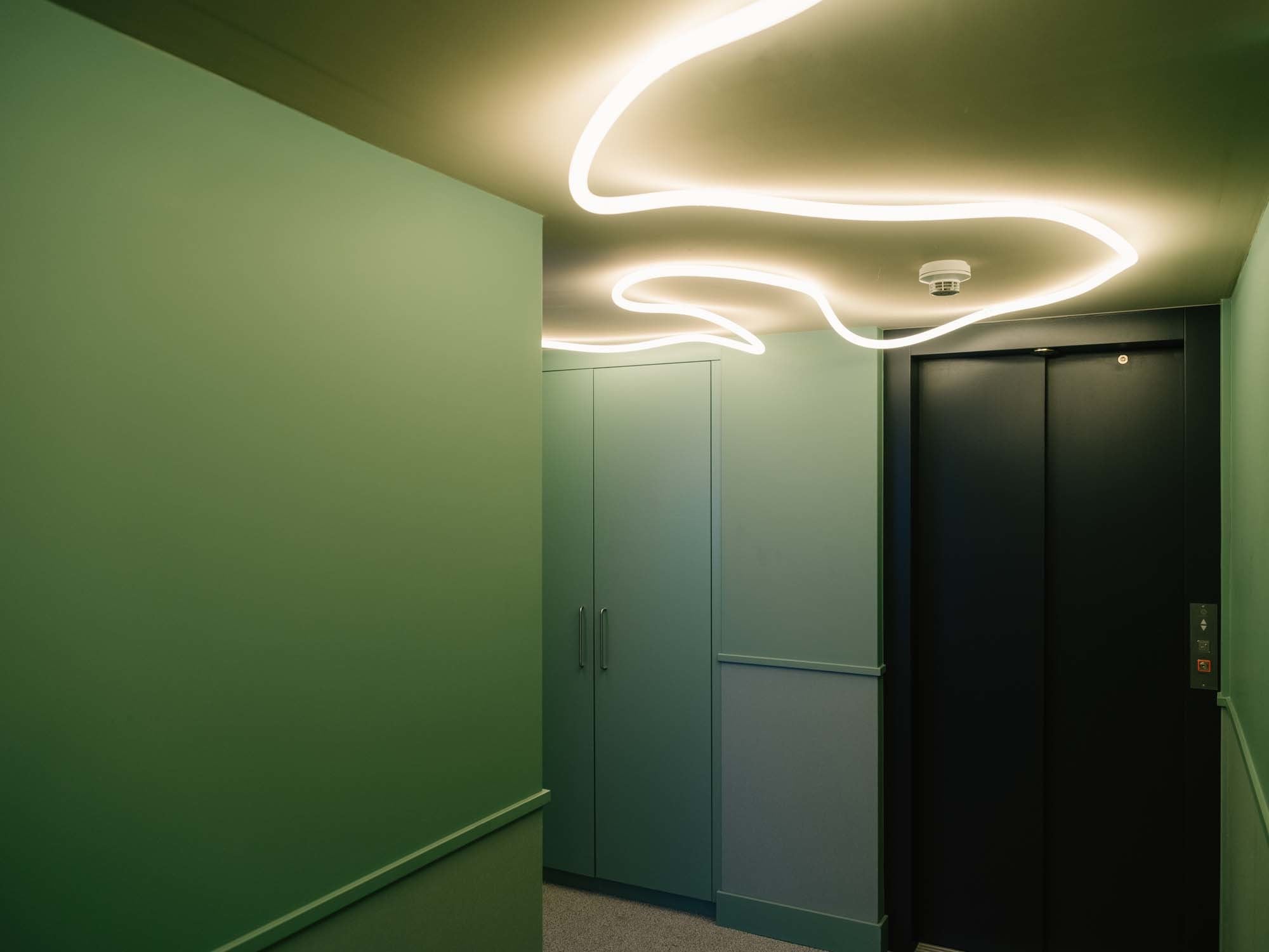 In den Waldgrün gehaltenen Kellergängen schafft La Linea von Artemide einen Kontrapunkt zur geradlinigen Architektur.