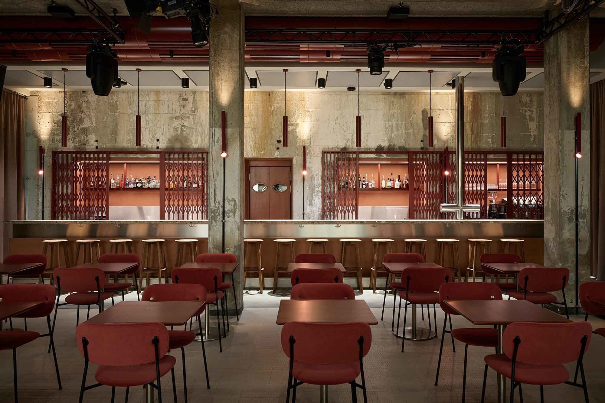 Der Live-Club Barbastelle empfängt Gäste in einem Raum voller roter Akzente und akustisch wirksamer Holzelemente.