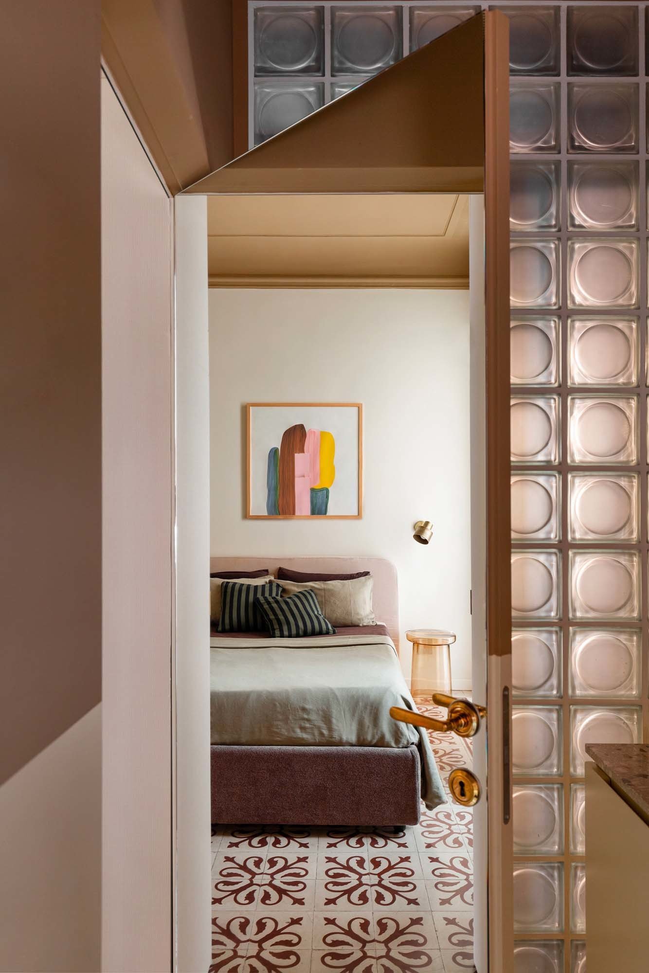 Das Schlafzimmer mit den historischen Zementfliesen spiegelt sich in der Tür zum Hauptbad.