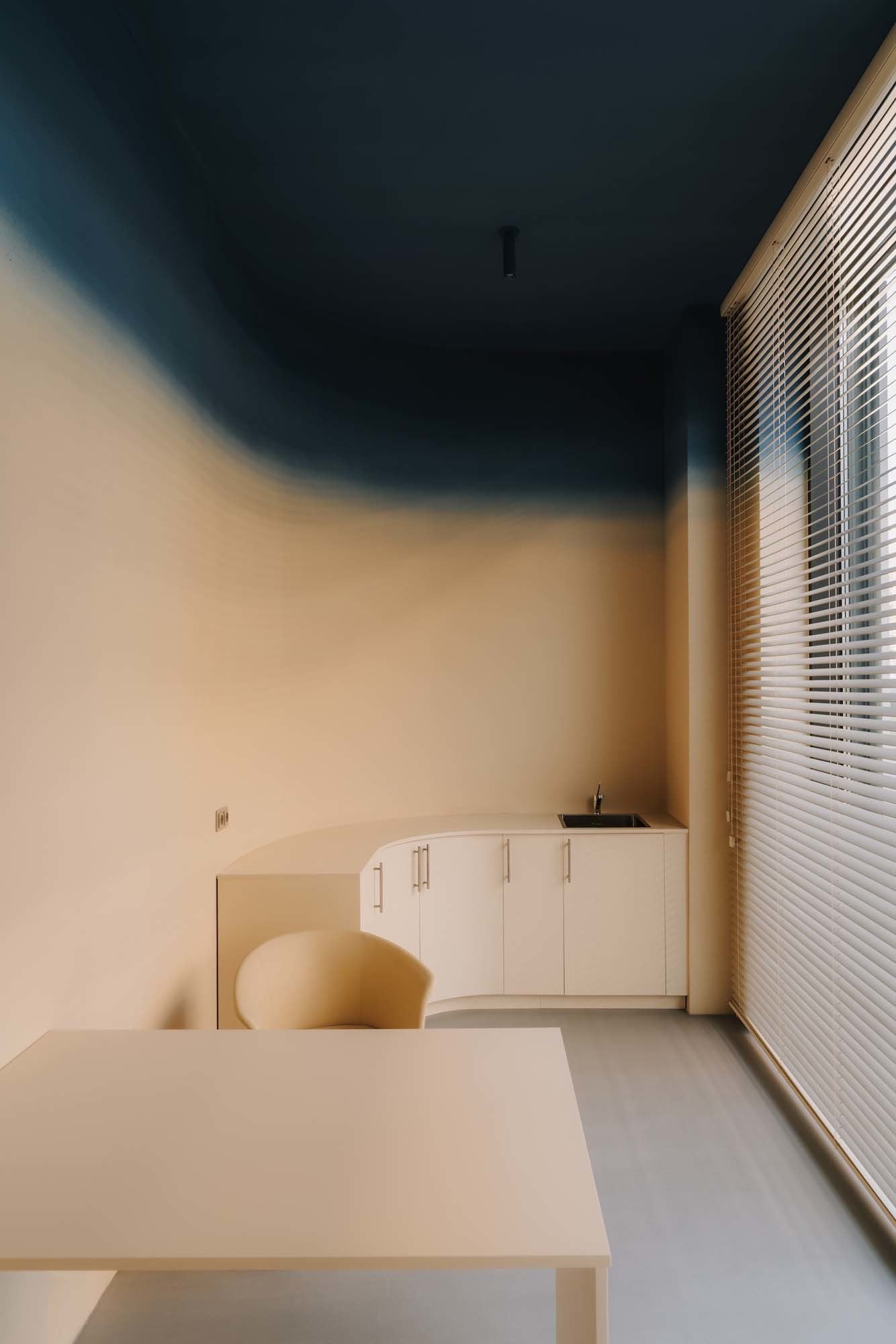 Ein blauer, immer dunkler werdender Farbverkauf mündet in einer marineblauen Decke im Untersuchungszimmer. Er spielt auf den Purkinje-Effekt an, der im Dämmerlicht blaue Farben heller erscheinen lässt.