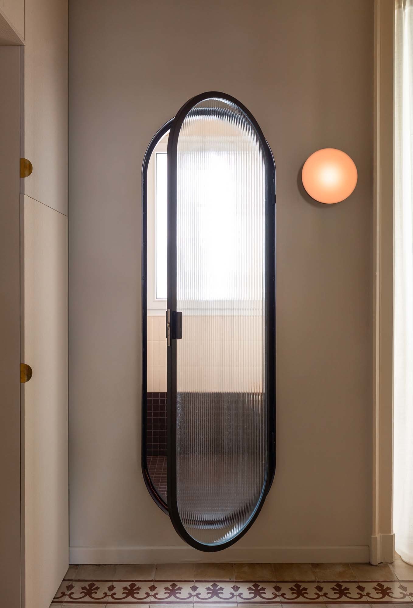 Mit spielerischer Note: Die Dusche betritt man durch eine ovale Tür aus geriffeltem Glas.