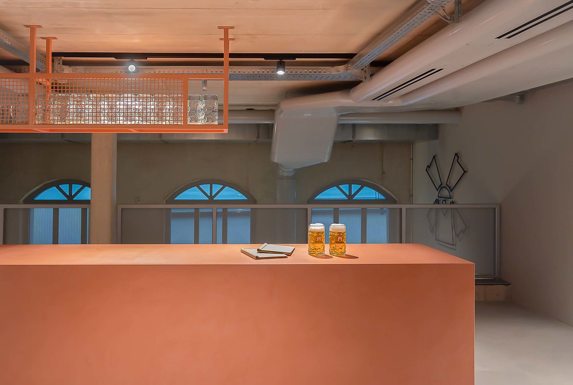 Eine reduzierte Thekenanlage trifft auf funktionale Metallregale und sichtbare Haustechnik – industriell im Ausdruck, klar strukturiert im Detail.