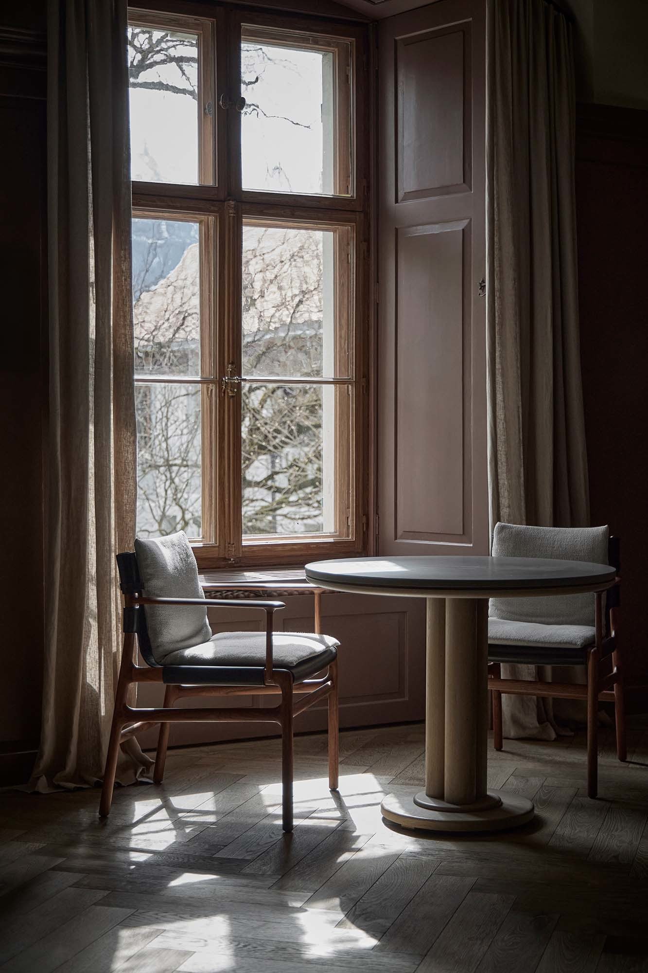 Speisesaal mit Schattenspiel: Gedämpftes Licht und hochwertige Möbel – wie die Stühle Sela von De La Espada – schaffen Raum für Genuss.