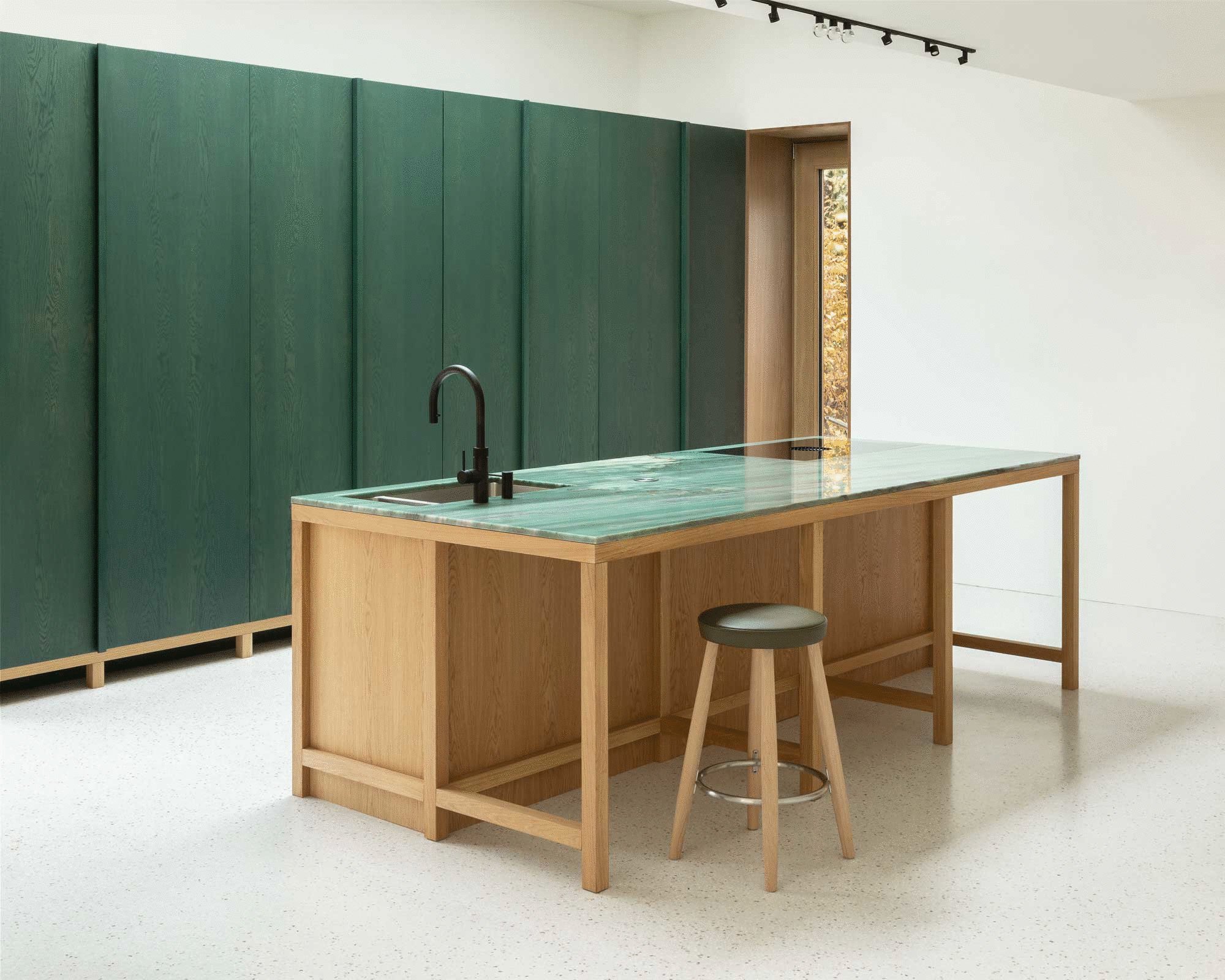 In der Küche des von O’Sullivan Skoufoglou Architects umgebauten Einfamilienhauses Fohlenweg in Berlin bilden die maßgefertigten, dunkelgrün gebeizten Wandschränke und die smaragdgrüne Quarzit-Arbeitsplatte einen markanten Kontrast.