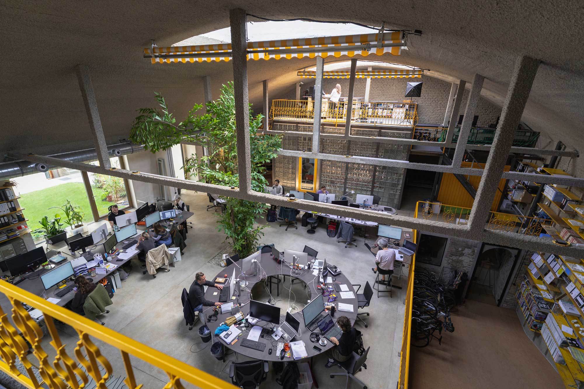 Vom Wiener Mietpalais in die Garage: Caramel ArchitektInnen haben sich eine offene Arbeitslandschaft im Bestand mit Pferderampe, Dorfplatz und maisgelben Akzenten gestaltet.