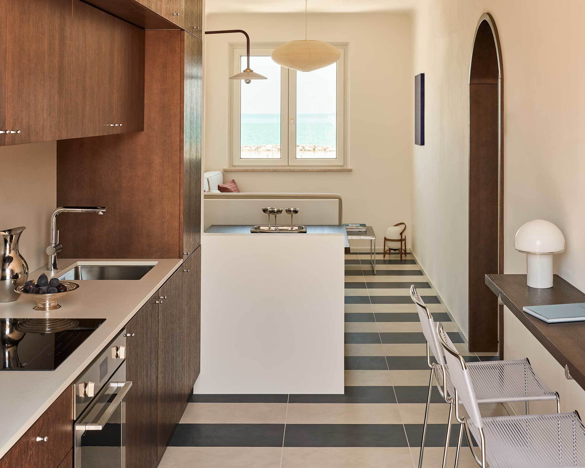 Beim Umbau einer Ferienwohnung in den Marken griff das norditalienische Architekturbüro DEDABO auf die Erfahrung von Bootsbauer*innen zurück. Eine maßgefertigte Küche im nautischen Stil, eine klare Raumgliederung und ein gestreifter Boden lassen die 66 Quadratmeter größer wirken, als sie tatsächlich sind.