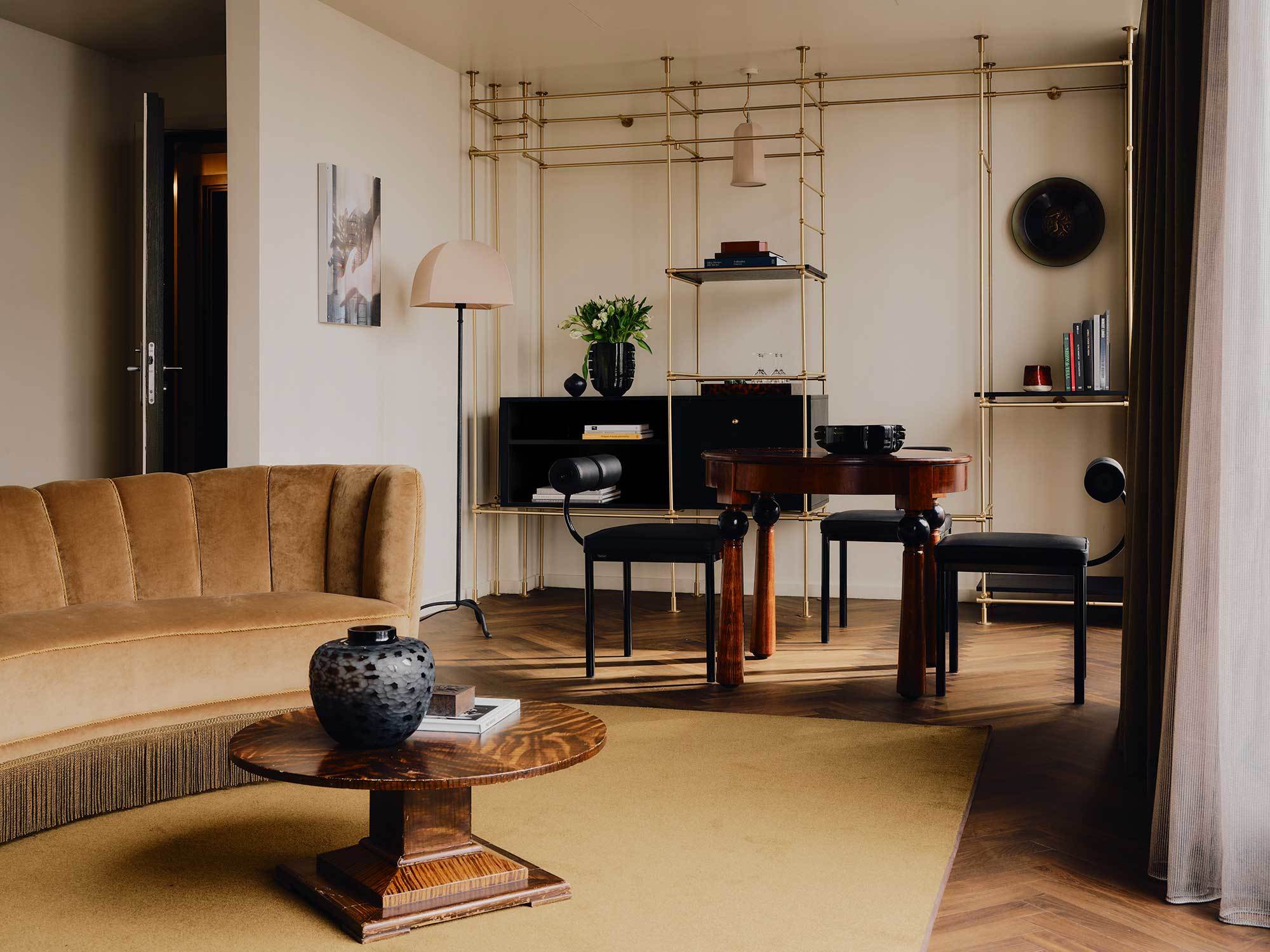 In der Prestige Suite gesellt sich ein geschwungenes Samtsofa mit Fransen zu einem kantigen Metallregal mit Golddetails.