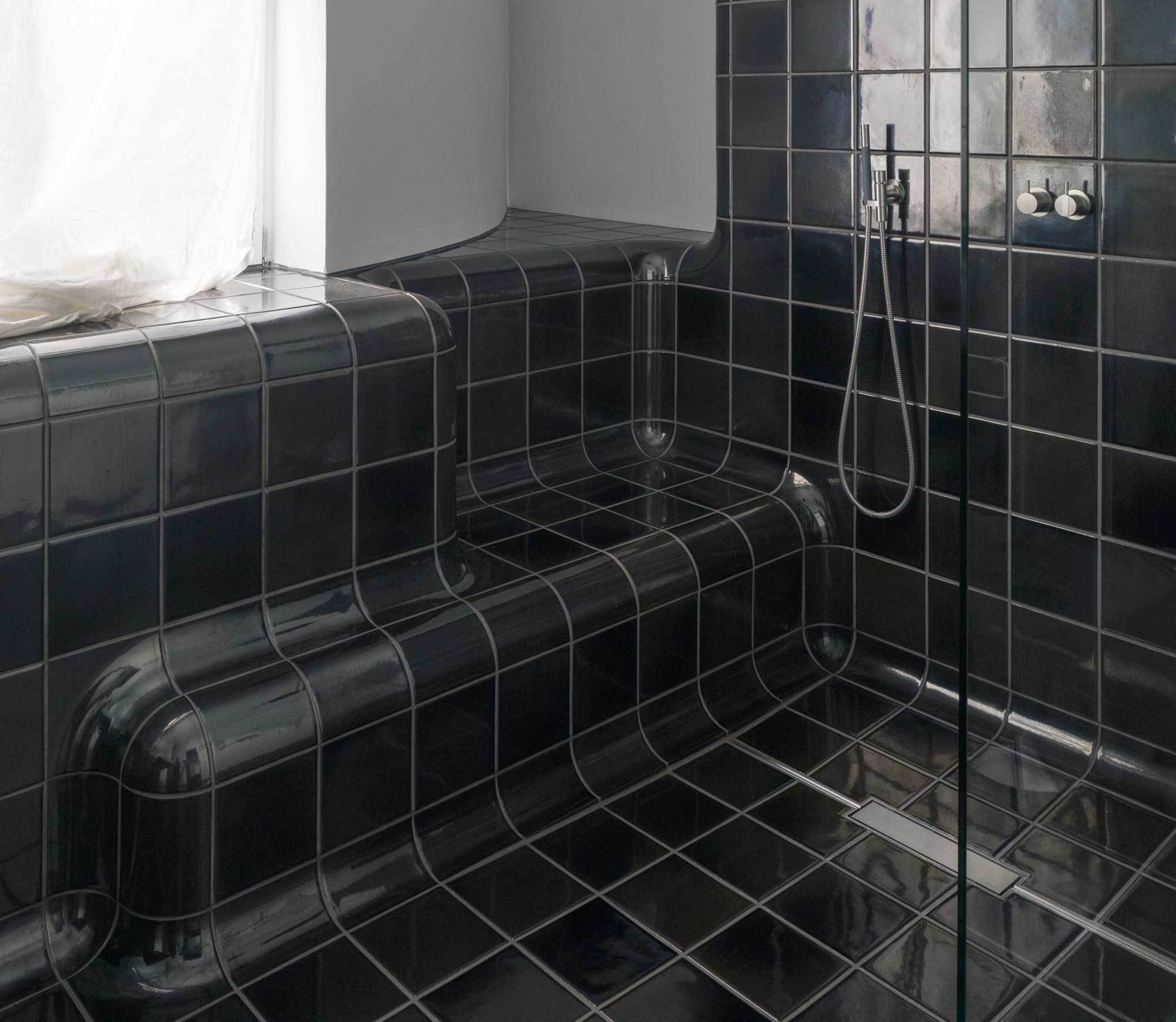 Im Bad des Projekts Hermannstrasse in Berlin formen glasierte Fliesen mit abgerundeten Kanten fließende Übergänge zwischen Boden und Wand.