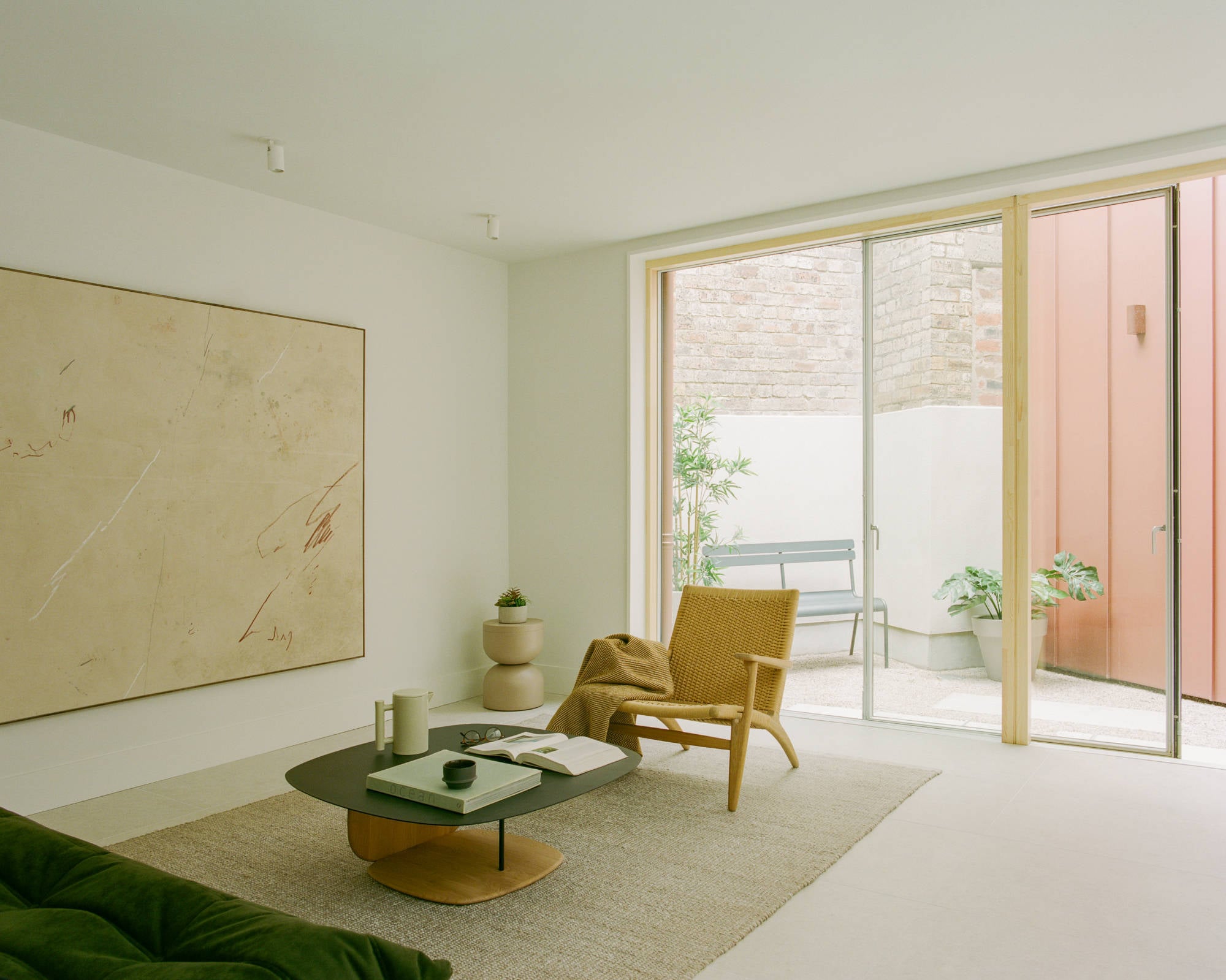 Große Holzrahmen-Schiebetüren öffnen den Wohnraum zum Innenhof und schaffen eine direkte Verbindung zwischen Innen und Außen.