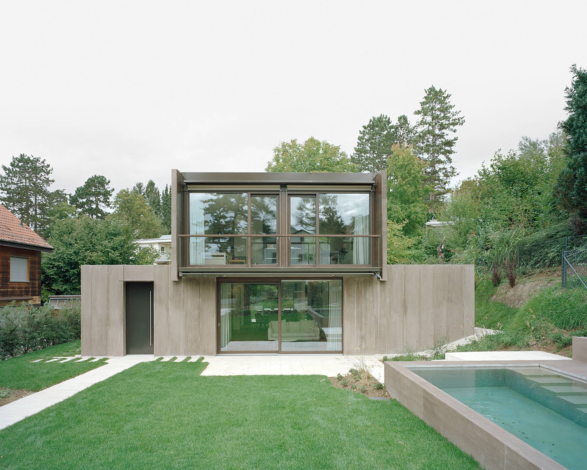 Das Wohnhaus von Patrick Reuter Architektur steht auf einem ehemaligen Flussbett und öffnet sich mit einem streng gefassten Pool zum Garten.