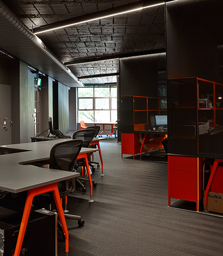 Grau, Schwarz, Neonorange: Semitransparente Schirme sorgen bei einer Anwaltskanzlei für semiprivate Kommunikationsbereiche.